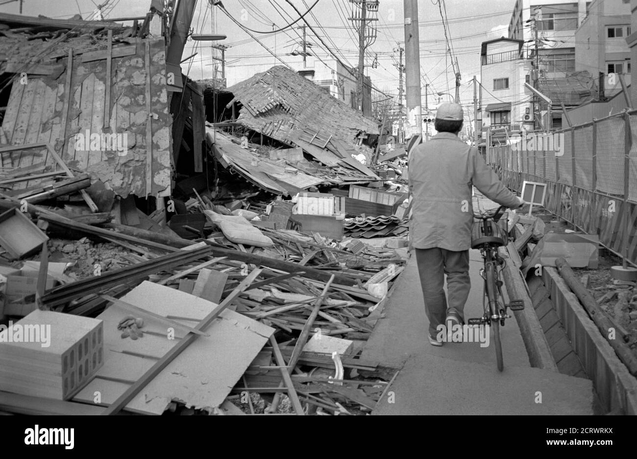 Man walks his bike through a path in the aftermath rubble of the damage caused from the 1995 Great Hanshin Earthquake in Kobe, Japan Stock Photo