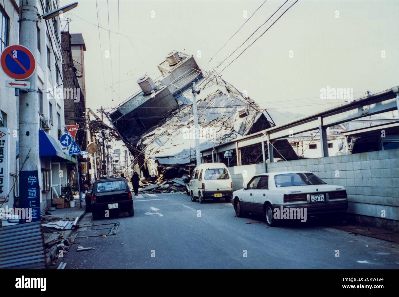 Building collapsed sideways down the road from the damage caused by the 1995 Great Hanshin Earthquake in Kobe, Japan Stock Photo