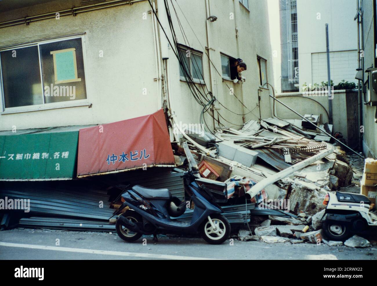 Man looks out of window of collapsed building damaged from the 1995 Great Hanshin Earthquake in Kobe, Japan Stock Photo