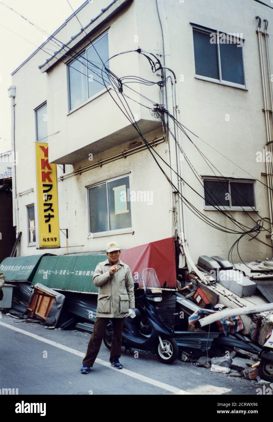 Man stands in front of YKK Fastner building collapsed from the damage caused by the 1995 Great Hanshin Earthquake in Kobe, Japan Stock Photo