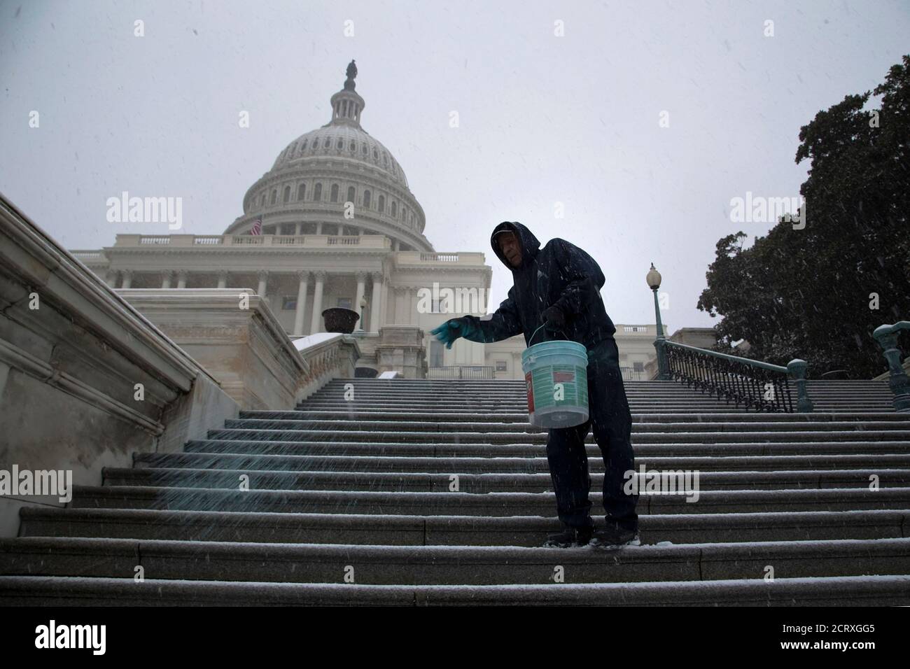 A worker spreads an anti-ice mix on the steps of the U.S. Capitol as light snow flurries fall in Washington December 8, 2013. REUTERS/Jonathan Ernst (UNITED STATES - Tags: POLITICS ENVIRONMENT SOCIETY) Stock Photo