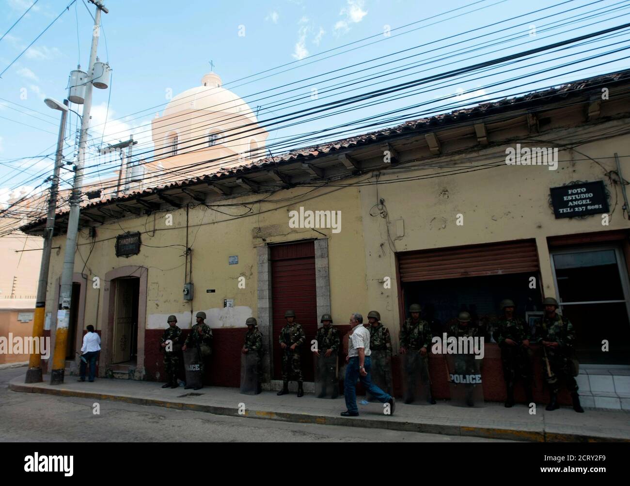 A man walks past soldiers standing guard in Tegucigalpa July 7, 2009. Ousted Honduran President Manuel Zelaya said on Tuesday he accepted the mediation of Costa Rican President Oscar Arias to try to solve his country's political crisis following the June 28 coup that ousted him. REUTERS/Henry Romero (HONDURAS POLITICS CONFLICT MILITARY) Stock Photo
