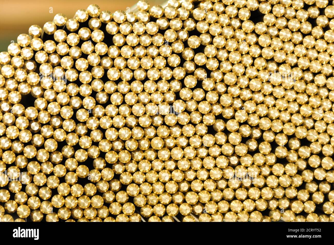 Background texture of the machined ends of brass rods packed tightly together in a warehouse or factory in a full frame view Stock Photo