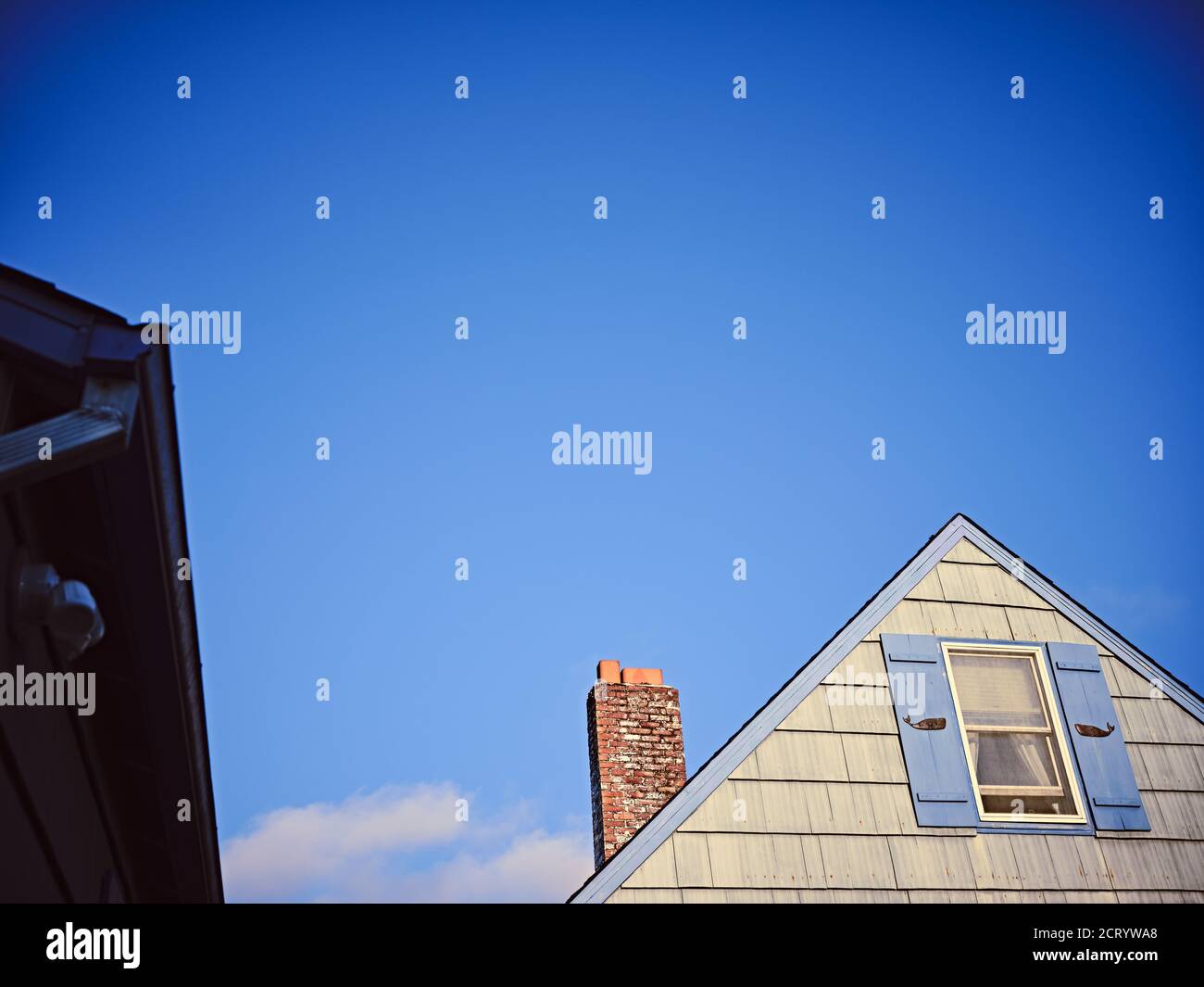 The chimney and peak of a beach house with whales on window shutters. Stock Photo