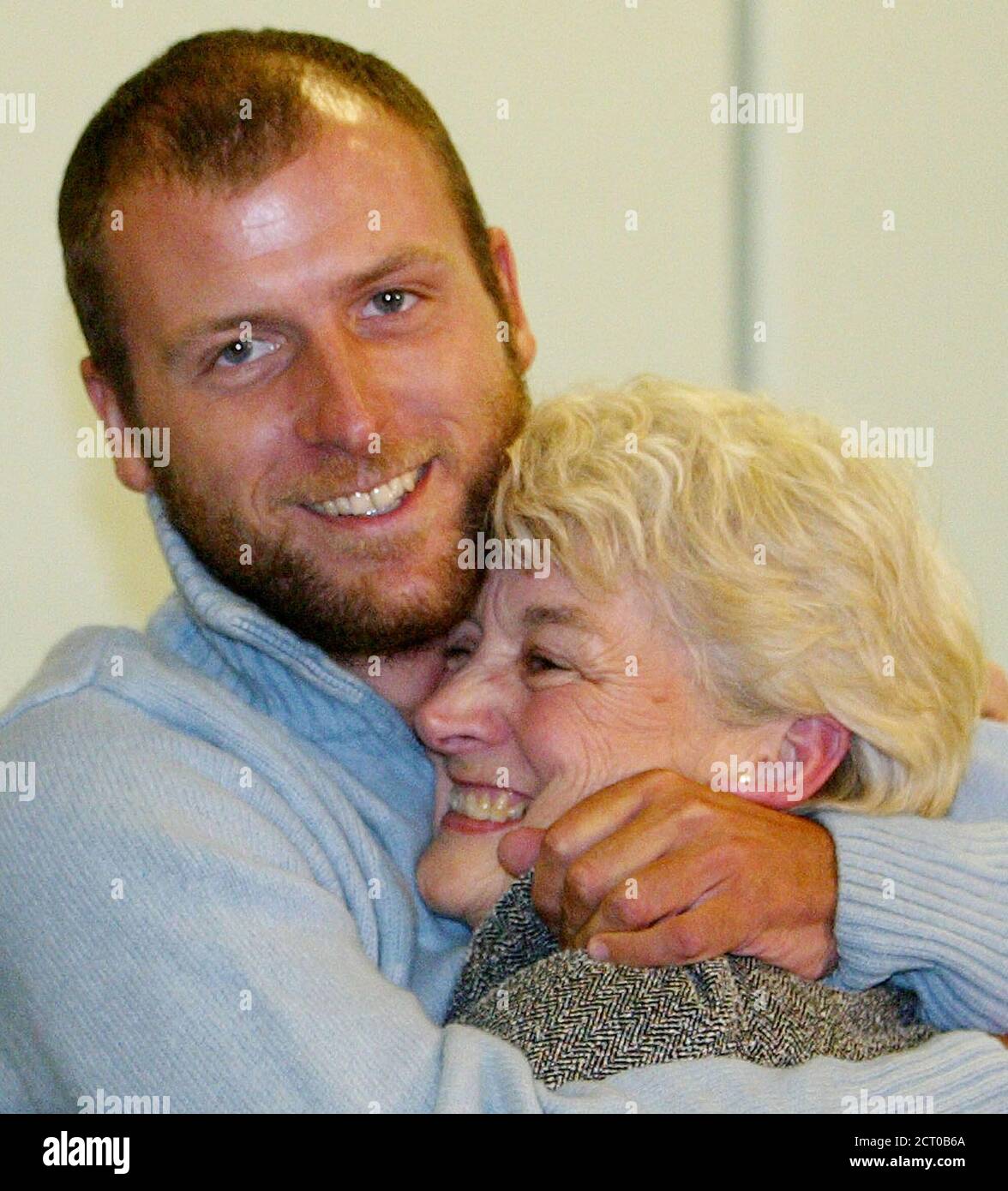 Britain's Mark Henderson (L) embraces his mother Sharelle during a news conference after his arrival at London's Heathrow airport, December 24, 2003. Henderson, who was held hostage for more than three months by Marxist rebels in Colombia, arrived back in England on Wednesday expressing huge relief and thanks to the people who negotiated his release. REUTERS/Toby Melville  TM/ASA/GM Stock Photo