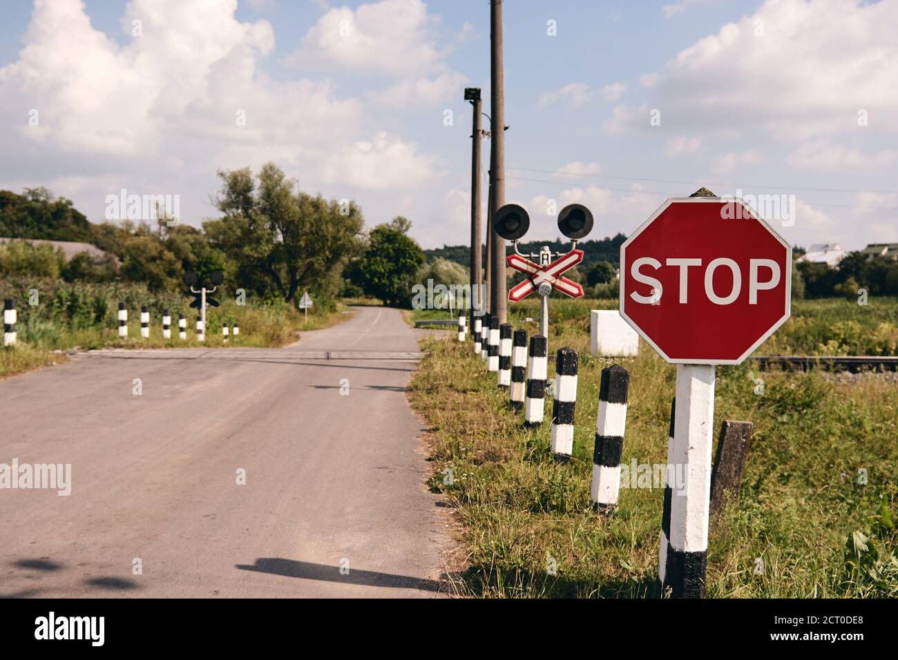 Railroad crossing with a Stop sign. Train rails in country landscape