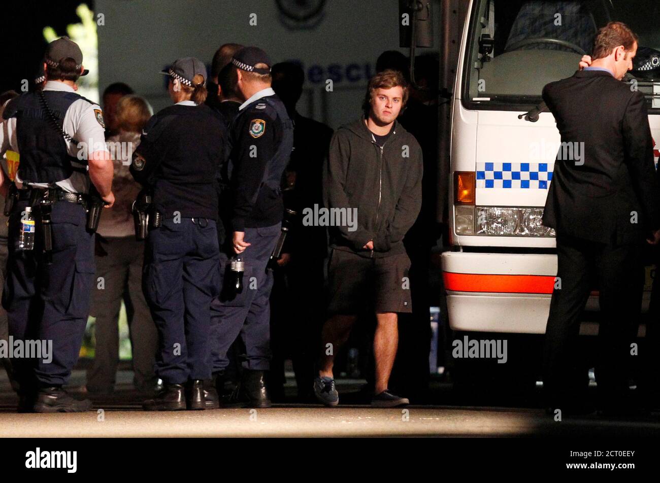 A youth walks between police outside a house bomb squad officers are working to protect an 18-year-old girl in the exclusive Sydney suburb of Mosman August 3, 2011. A young