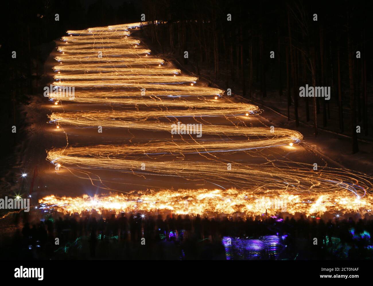 Hundreds of skiers and snowboarders hold lit torches and flashlights while descending from a slope during an annual festival in the Siberian town of Zheleznogorsk near Krasnoyarsk, Russia March 3, 2018. Picture taken with long exposure on March 3, 2018. REUTERS/Ilya Naymushin Stock Photo