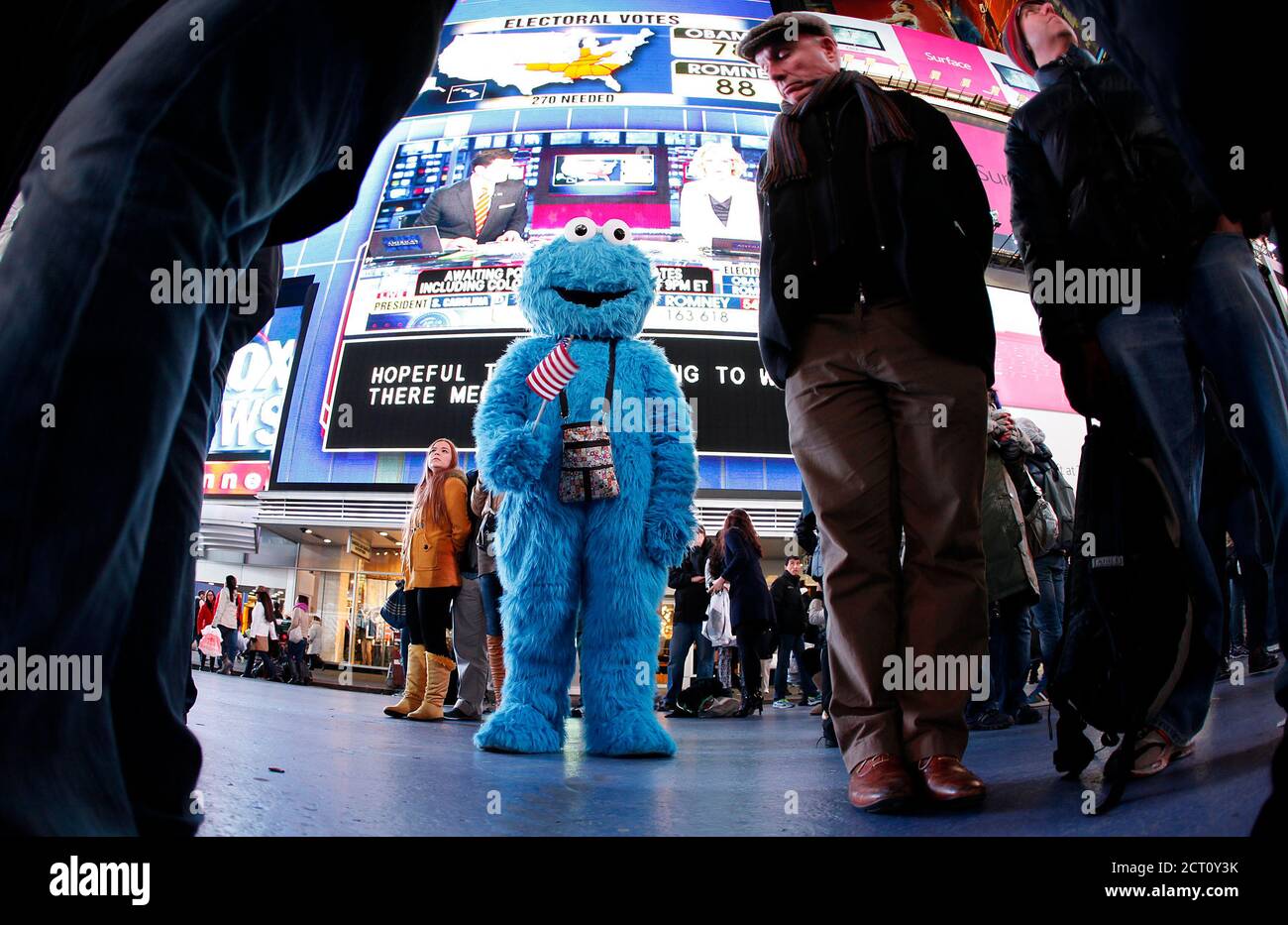 A man dressed as the character Cookie Monster watches TV screens in Times Square giving U.S presidential election results in New York November 6, 2012. REUTERS/Carlo Allegri  (UNITED STATES - Tags: POLITICS USA PRESIDENTIAL ELECTION ELECTIONS) Stock Photo