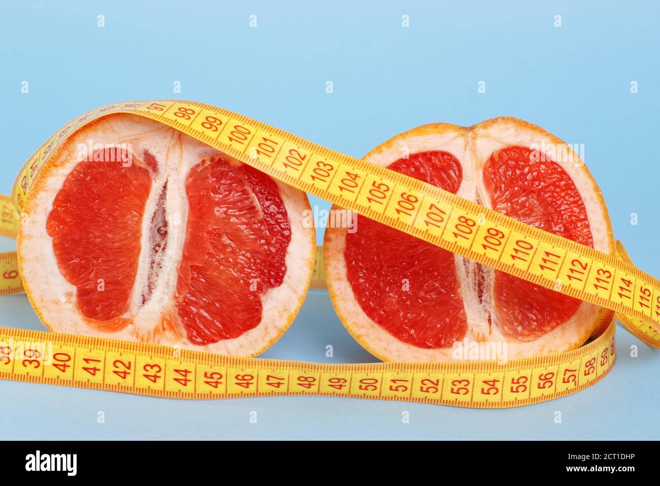 Two cut halves of juicy grapefruit with centimeter on blue background with copy space Stock Photo