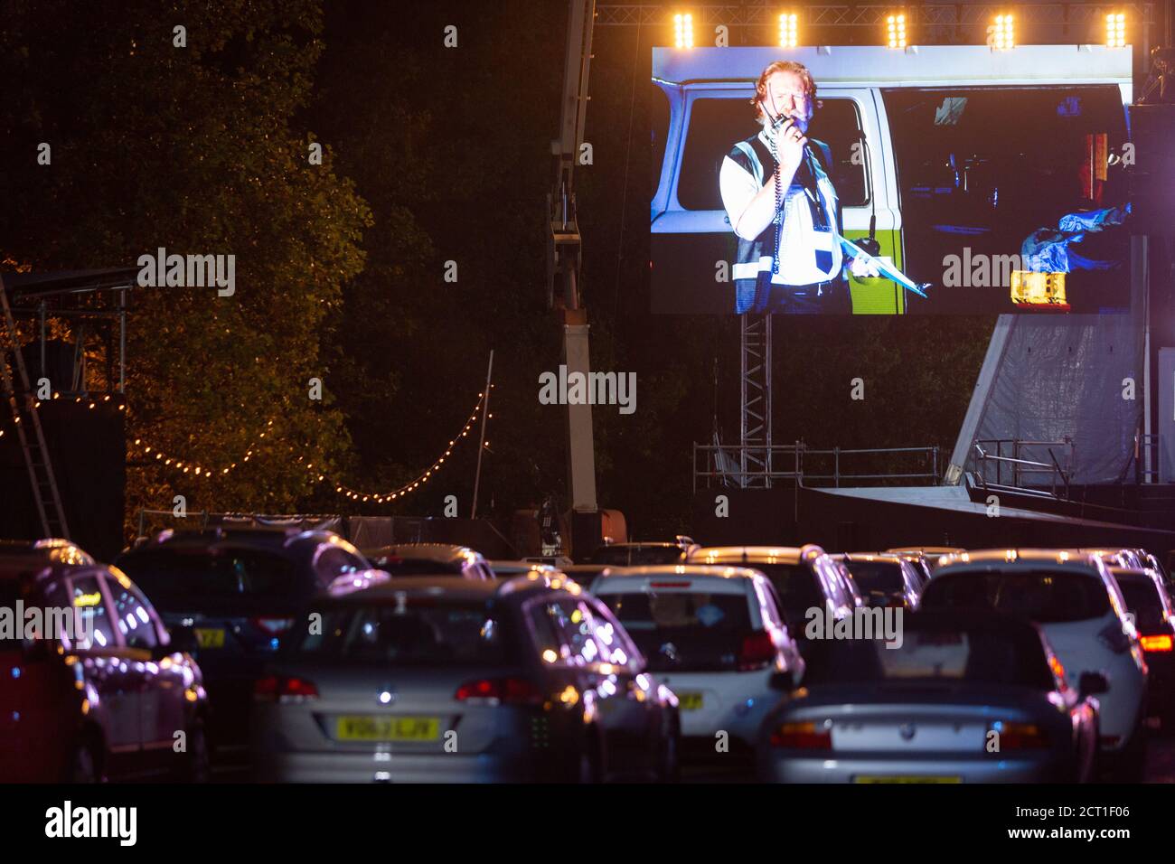 Rows of cars are parked in front of the stage to watch British Bass-baritone Paul Sheehan (playing Benoit) at the start of Puccini's La bohème, performed by members of  English National Opera (ENO) as a drive-in (ENO Drive and Live) at Alexandra Palace, on 18th September 2020, in London, England. This is ENO's first public performance since the closure of their West End Colisseum home venue, because of the Coronavirus pandemic lockdown in March. This is Europe's first live drive-in opera production that audiences can safely experience from their cars and ENO's first public performance since th Stock Photo