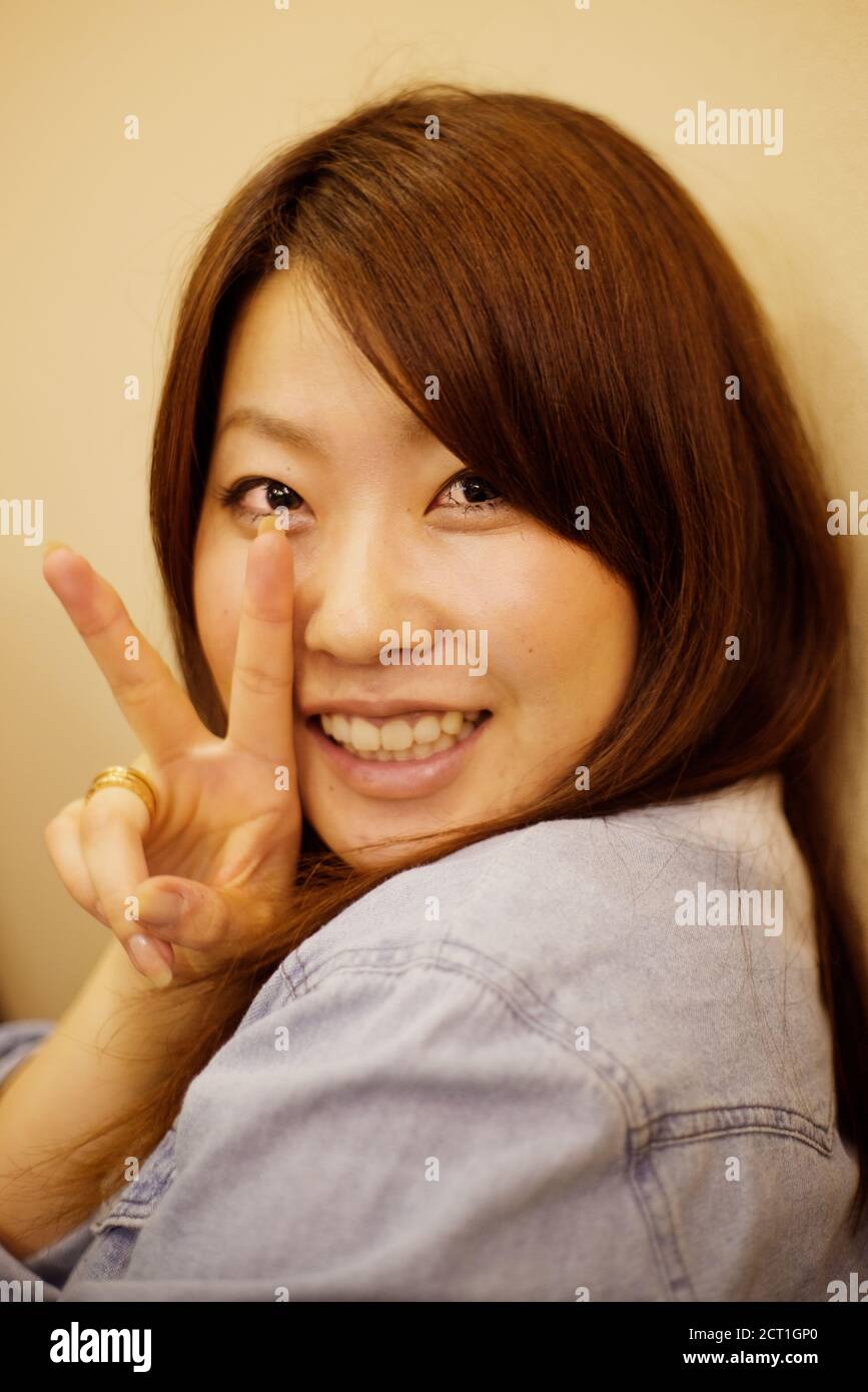 Japanese woman making V sign (hand gesture), in a restaurent at