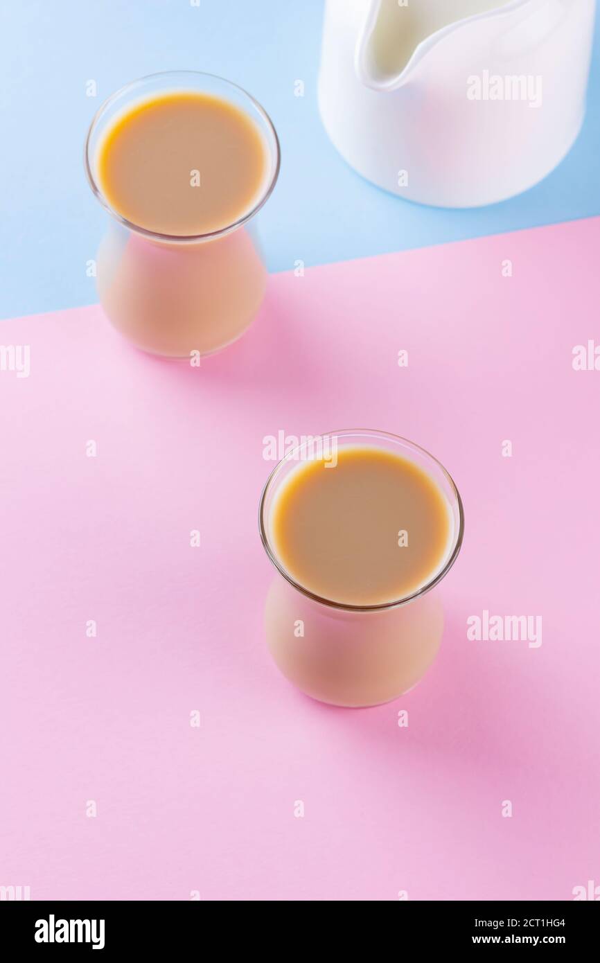 Milk tea on a pinkblue background. Turkish tea cups and milk jug. Cup