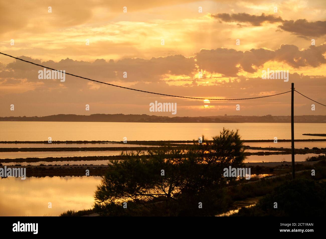 Dawn with golden clouds and sun rays at Estany Pudent salinas in Ses Salines Natural Park (Formentera, Balearic Islands, Mediterranean Sea, Spain) Stock Photo