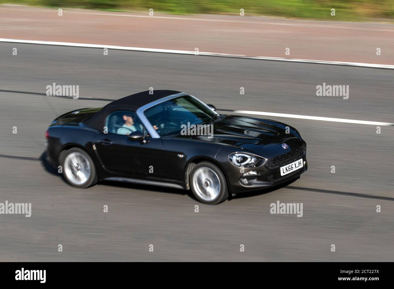 2016 Fiat 124 Spider Lusso + Multiair; Vehicular traffic moving vehicles, cars driving vehicle on UK roads, motors, motoring on the M6 motorway highway network. Stock Photo