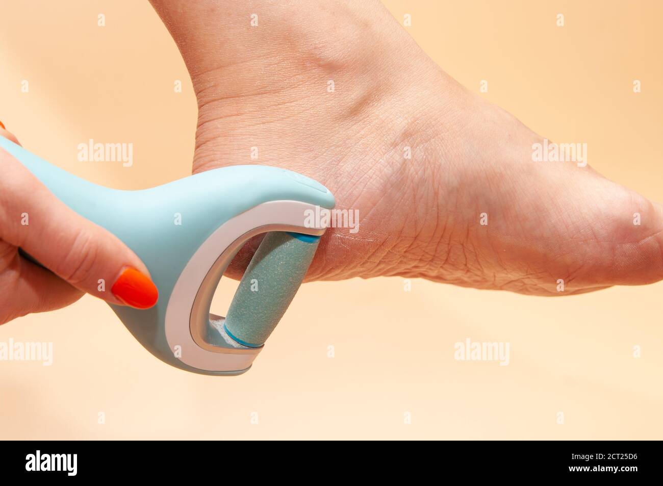 Care and cleansing of the woman feet from rough, flaky skin. An electric foot dead skin remover in a woman's hand grinds foot heel at home Stock Photo