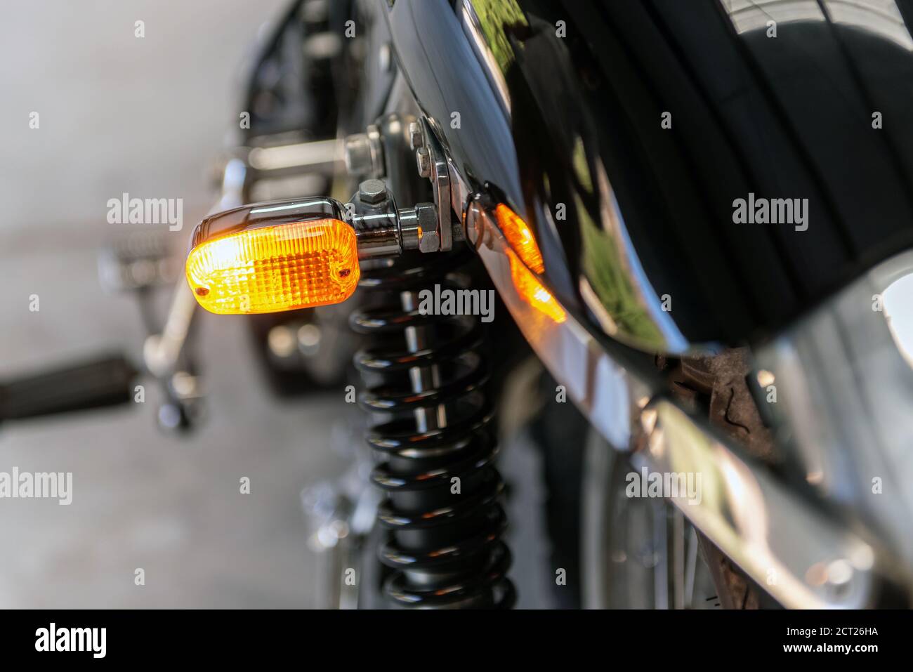 Rear lens of left turn light on vintage motorcycle shines bright as a warning to other drivers. Stock Photo