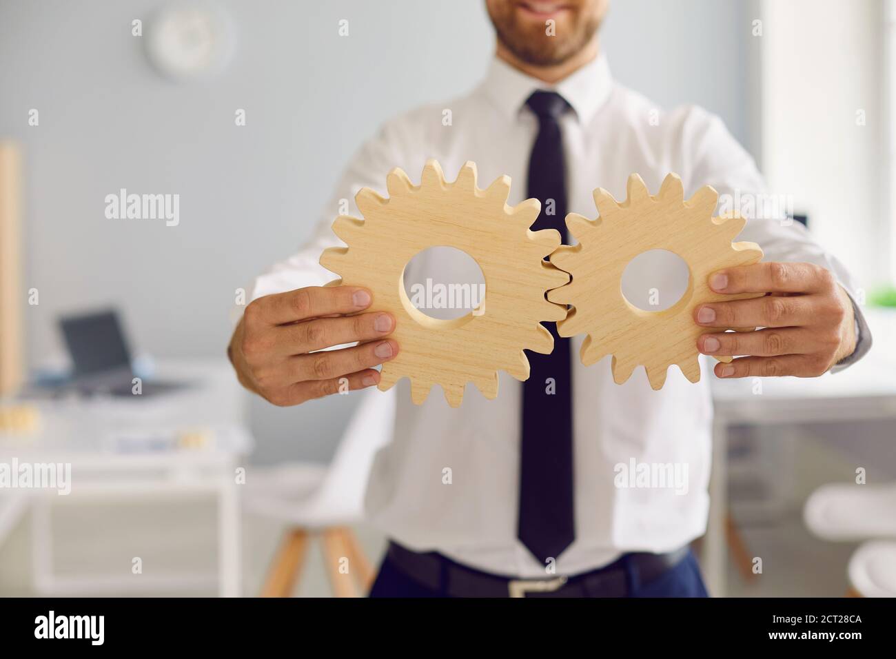 Cropped businessman holding 2 cogwheels that fit perfectly as metaphor for effective business system Stock Photo