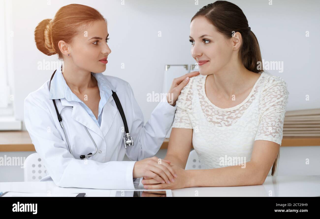Woman-doctor reassuring her female patient while sitting at the desk ...