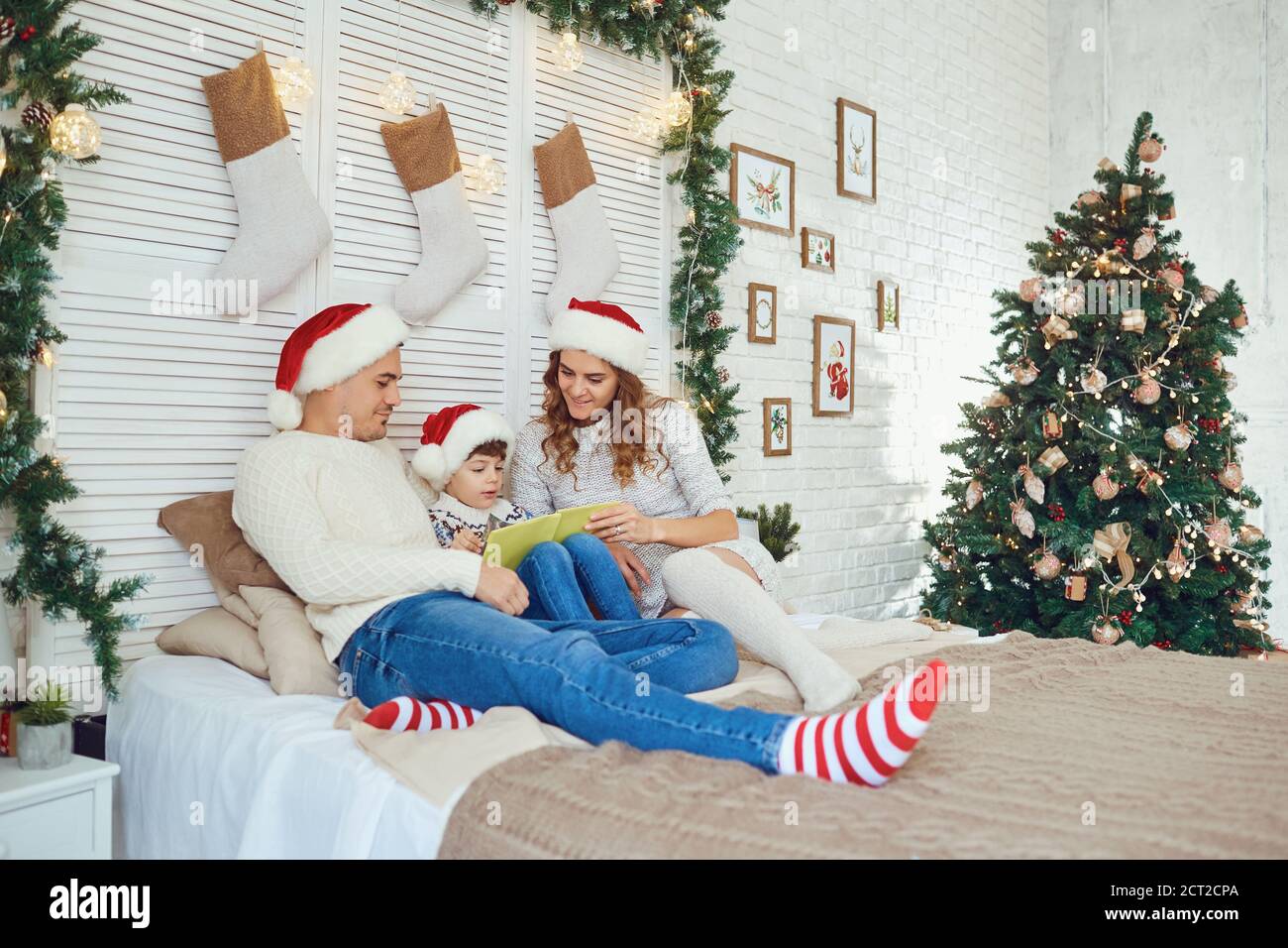 Family reading a bookin a house with a Christmas tree. Stock Photo