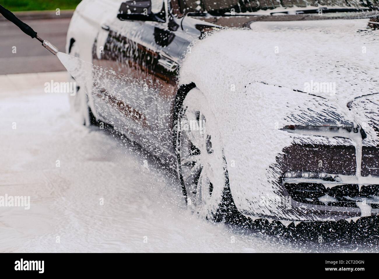 Washing black car. Automobile cleaning with foam water. Transport