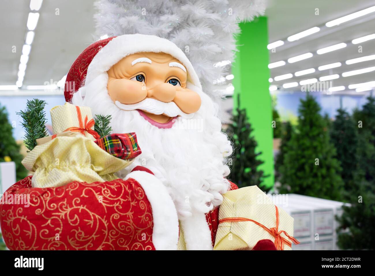 Portrait of a puppet Santa Claus close-up side view. Smiling Christmas santa carrying gifts in his hands. Sale christmas tree on background Stock Photo