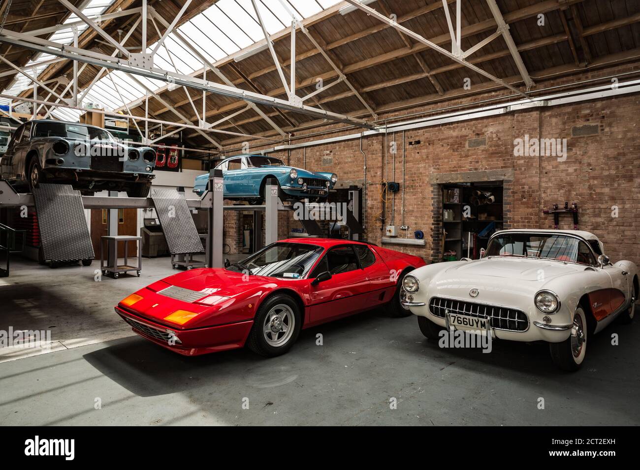 A Classic car garage at the Bicester Heritage Sunday scramble with a 1957 Chevrolet Corvette C1, a Ferrari 512BB, a Ferrari 250GTE and a Jaguar XJ Stock Photo