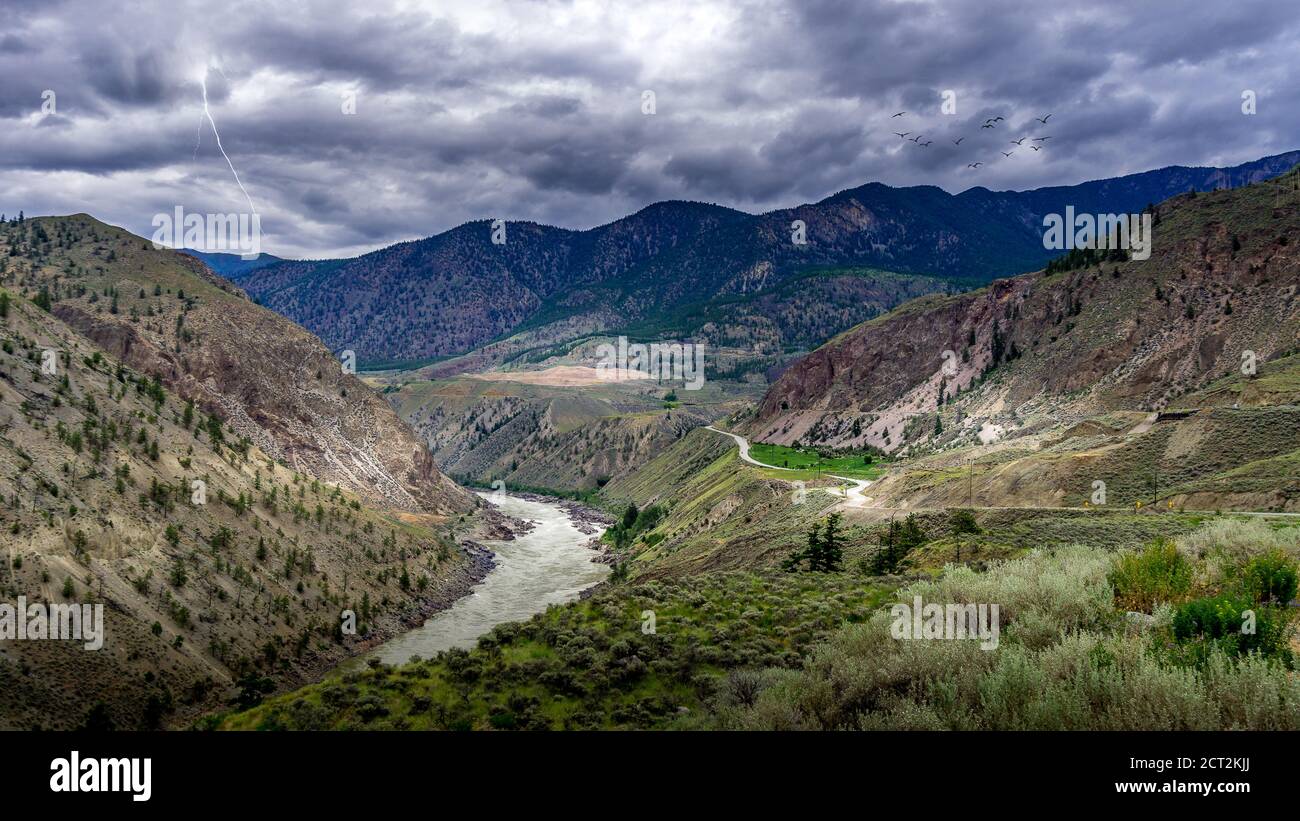 Lightning Strike and a Flock of Birds in Bad weather hanging over the Fraser Canyon and Highway 99 near Lillooet in British Columbia, Canada Stock Photo