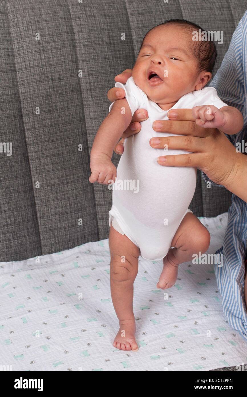 3 week old newborn baby boy, reflex stepping,  walking motion when held upright with weight on feet Stock Photo