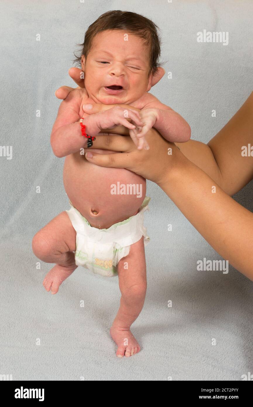 12 day old newborn baby boy demonstrating stepping reflex in diaper wearing good fortune bracelet Stock Photo