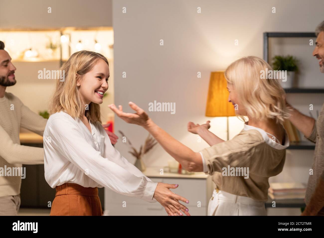 Happy young blond female going to embrace her mother while visiting parents Stock Photo