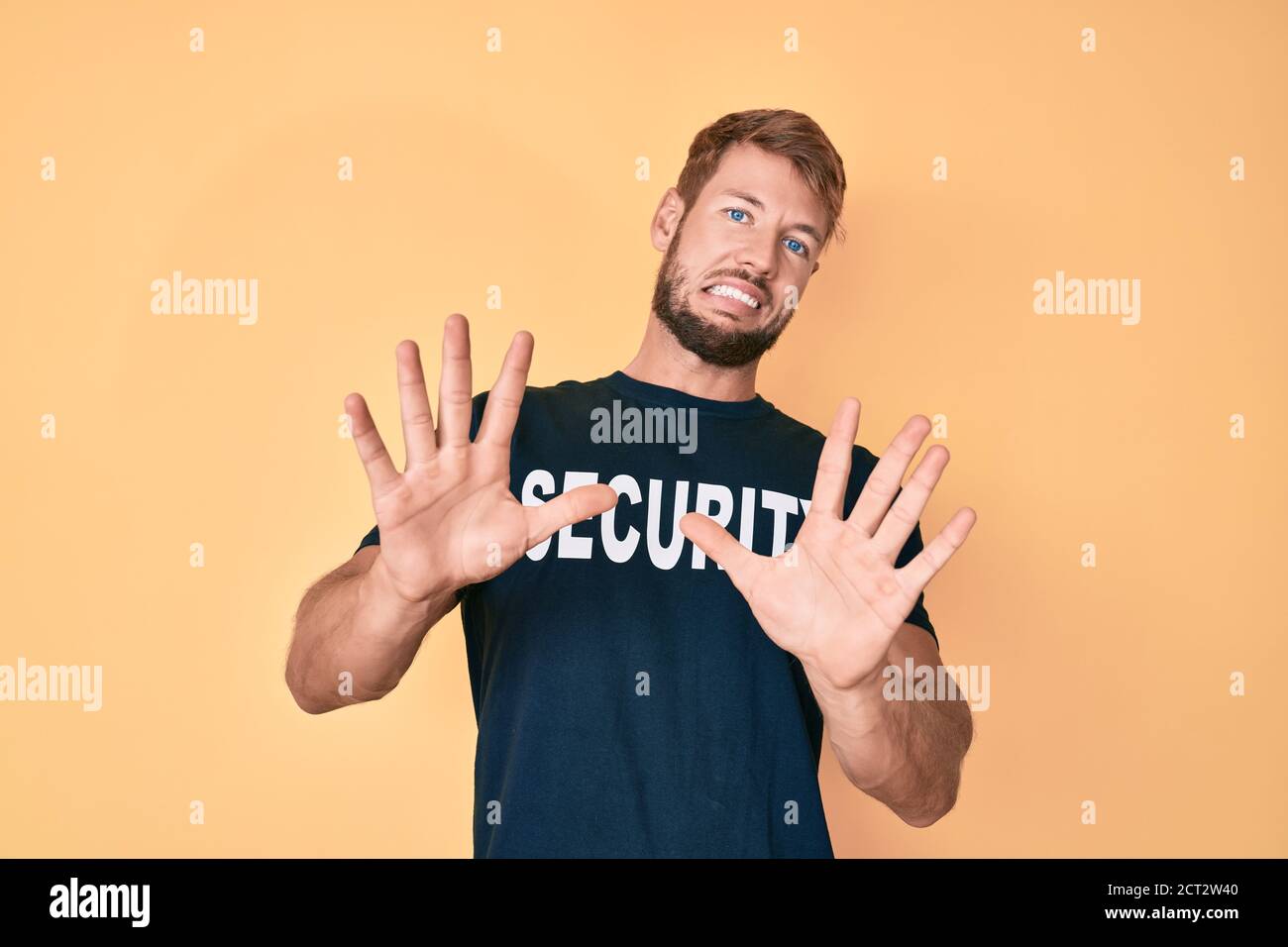 Young caucasian man wearing security t shirt afraid and terrified with ...