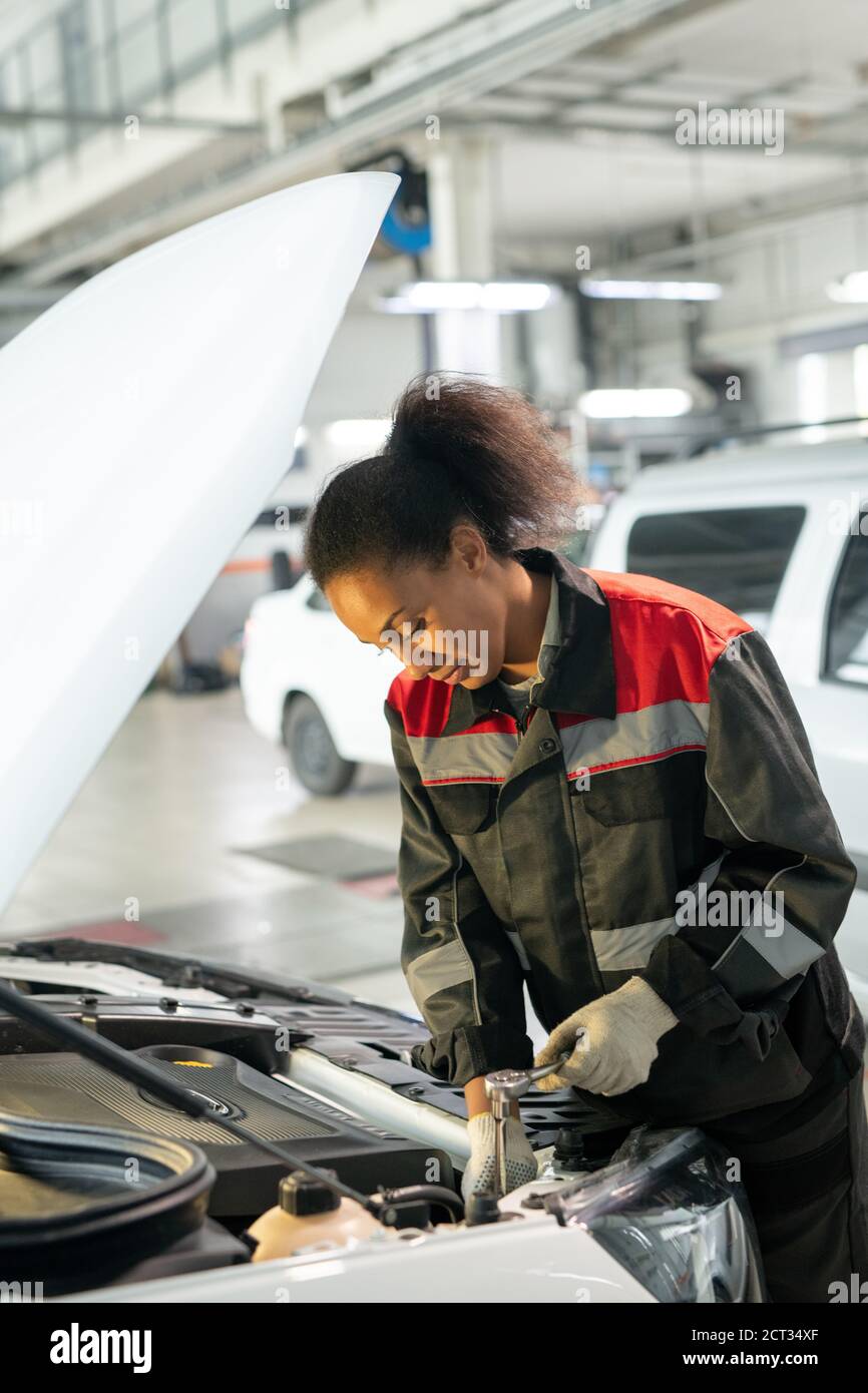 Young worker of car maintenance service standing by open engine compartment Stock Photo