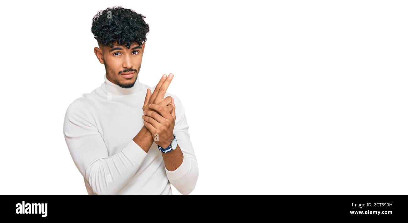 Young arab man wearing casual winter sweater holding symbolic gun with hand  gesture, playing killing shooting weapons, angry face Stock Photo - Alamy