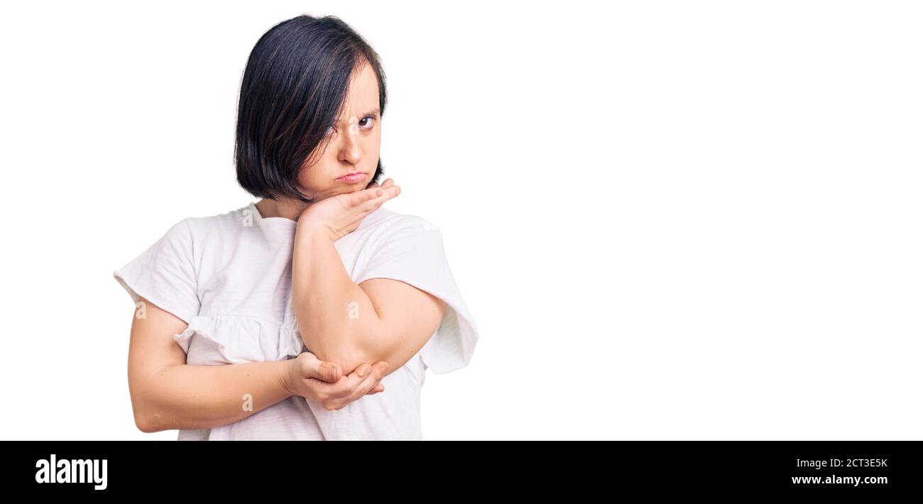 Brunette woman with down syndrome wearing casual white tshirt thinking looking tired and bored with depression problems with crossed arms. Stock Photo