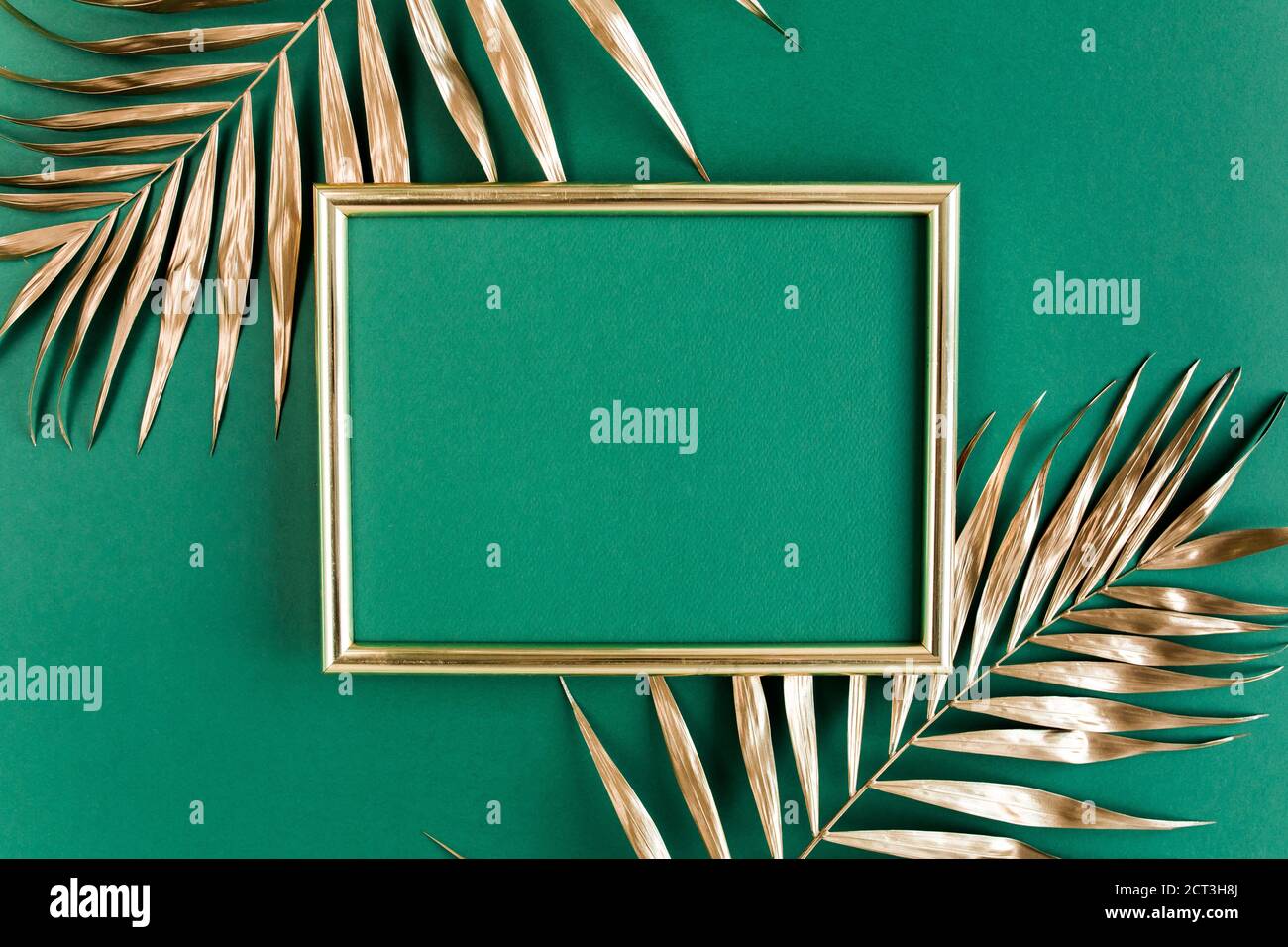 Gold tropical palm leaves and photo frame on green background. Flat lay ...