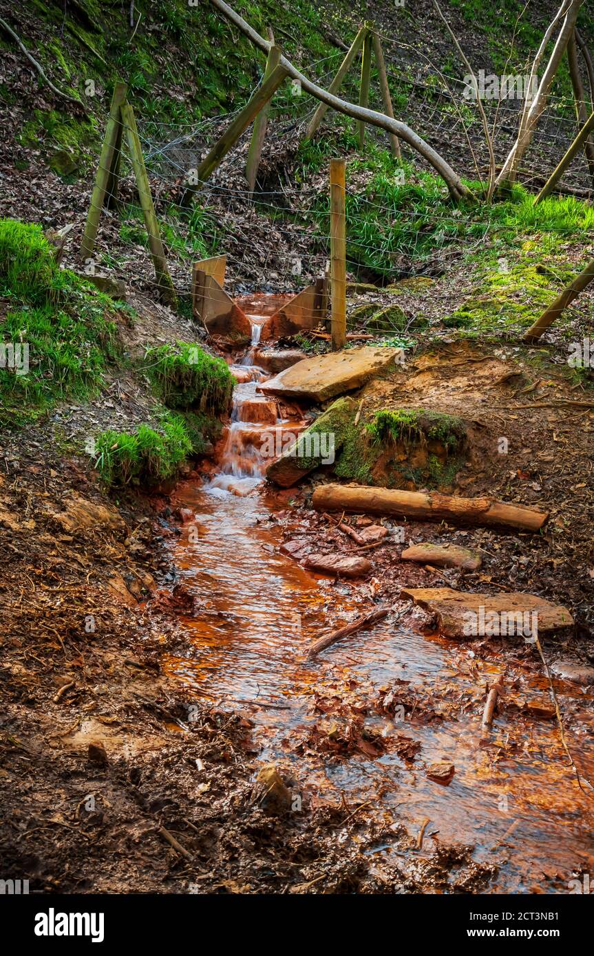 Ochre-stained outfall from an old ganister mine at Ryecroft Glen in Ecclesall Woods, Sheffield Stock Photo