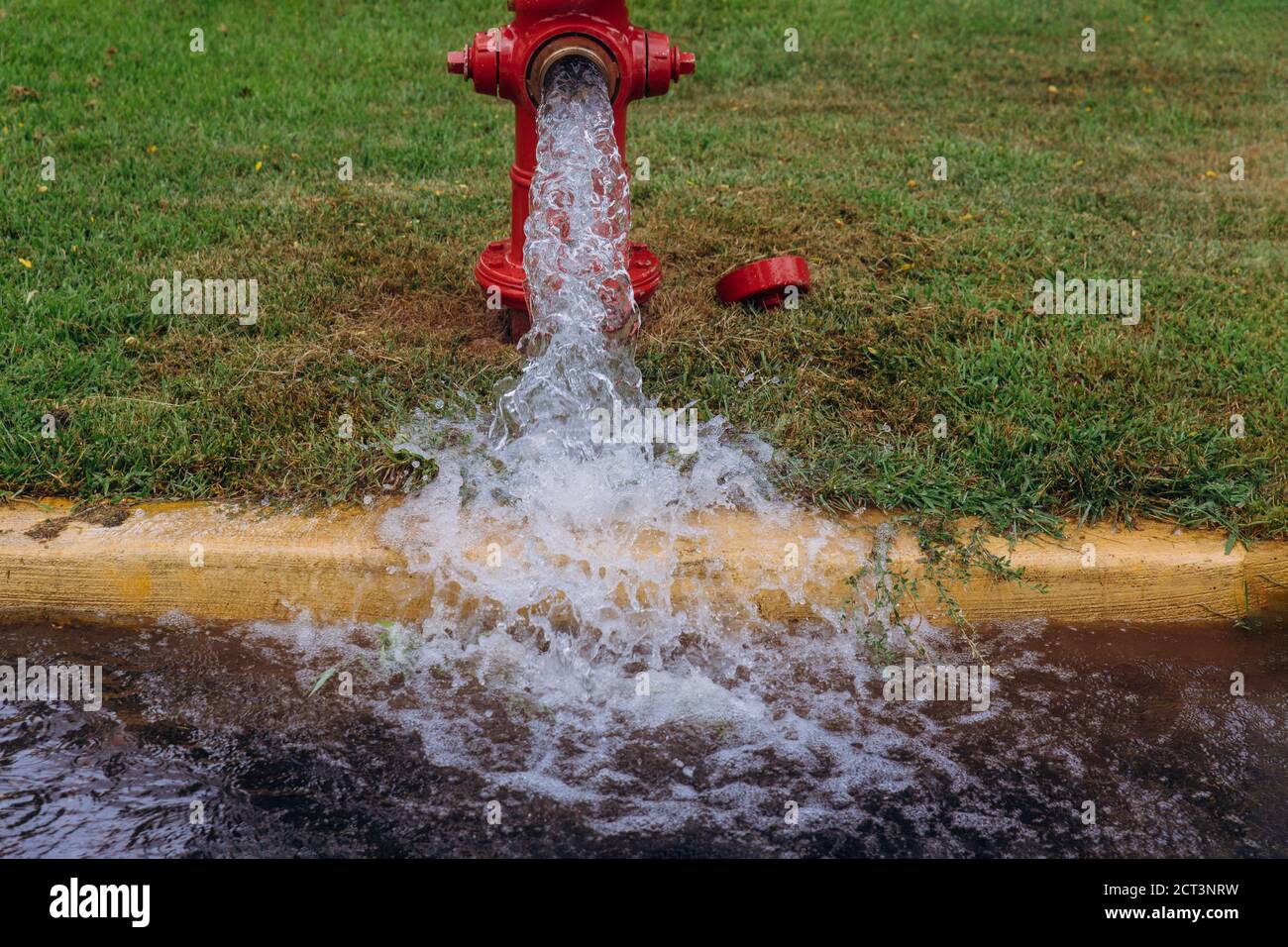 Open fire hydrant water flowing from open fire hydrant on street Stock