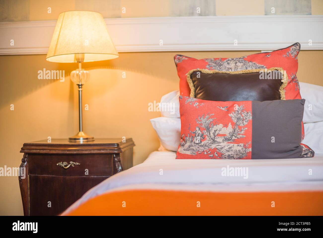 Bedroom home interior with red cushions, bed, wooden bedside table and lamp at a luxury boutique hotel, Buenos Aires, Argentina, South America Stock Photo