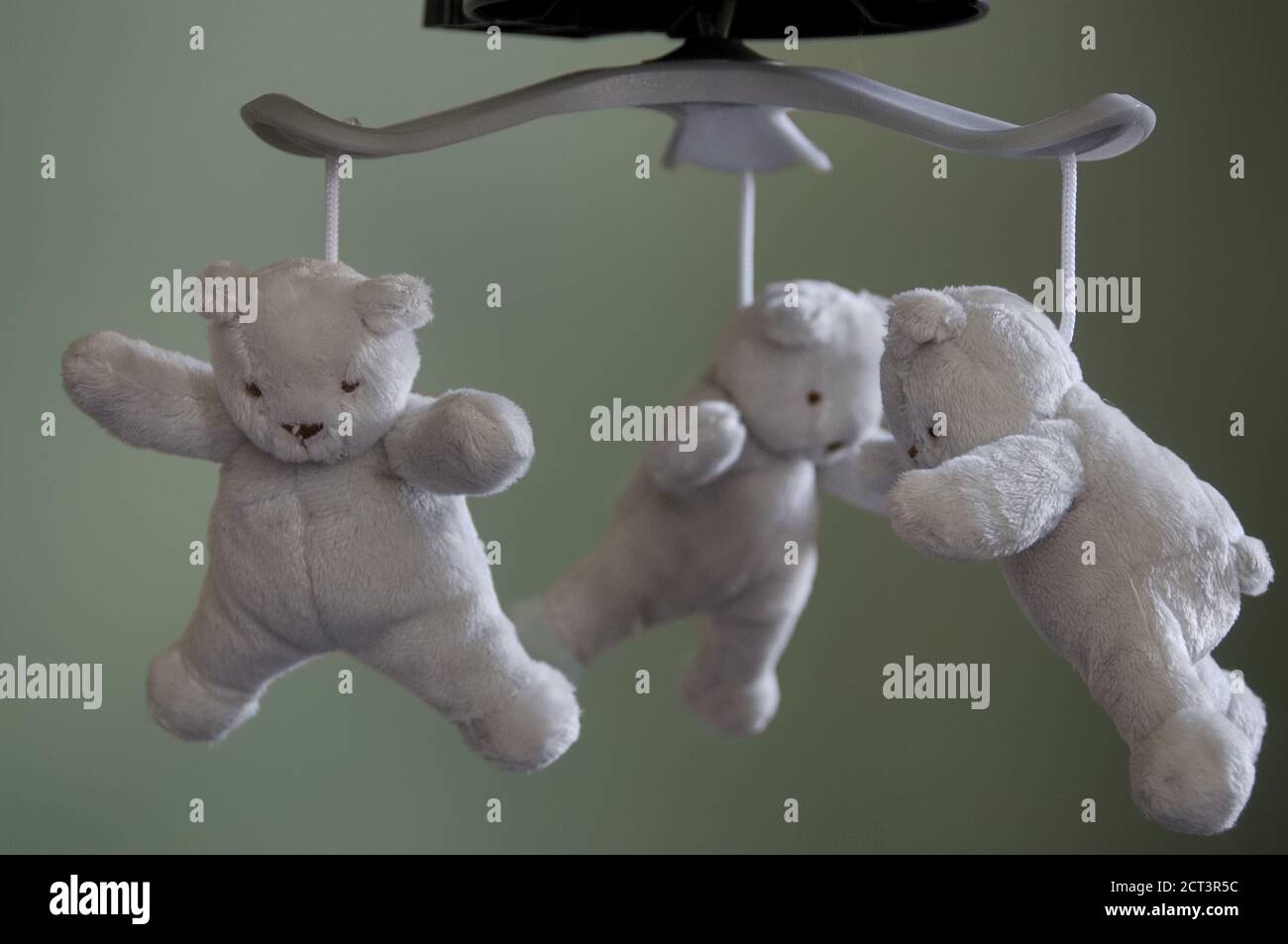 Three plush grey, white teddy bears hanging from a baby mobile, focus on foreground Stock Photo