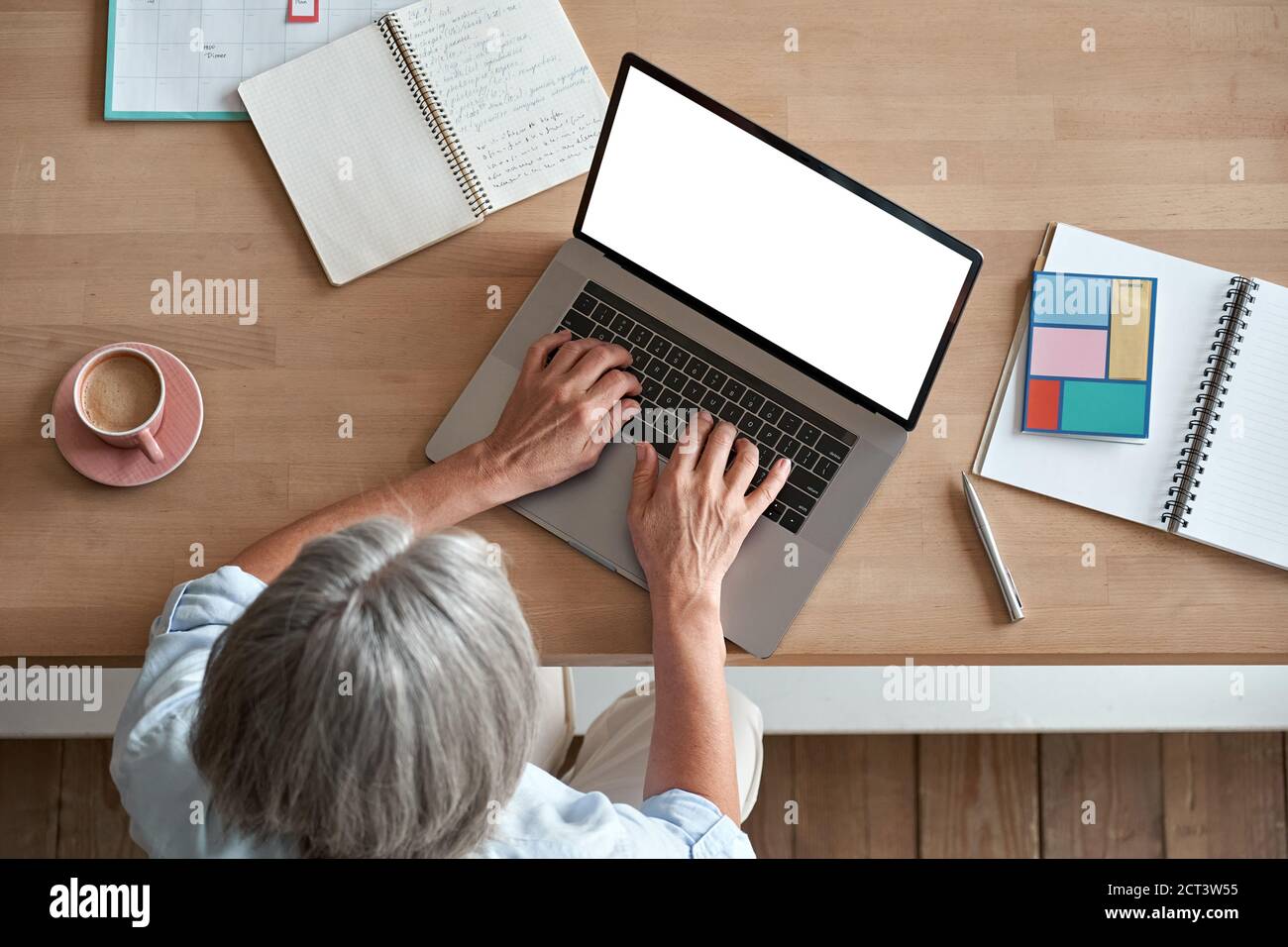 Mature middle aged woman using laptop computer sitting at workplace, top view. Stock Photo