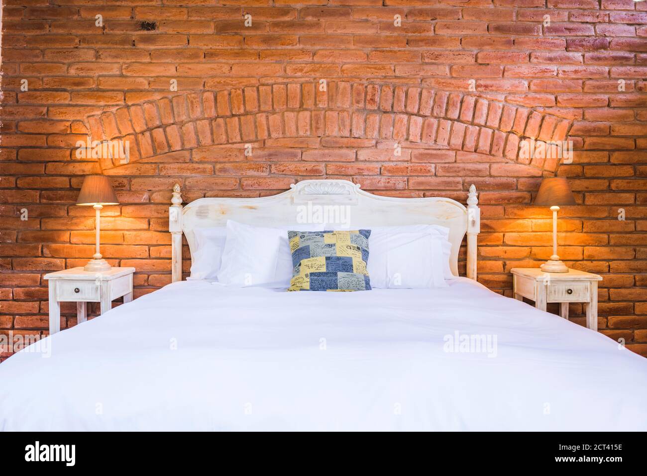 Bedroom at luxury house and hotel with exposed brick wall and bedside table and lamp, Ecuador, South America Stock Photo