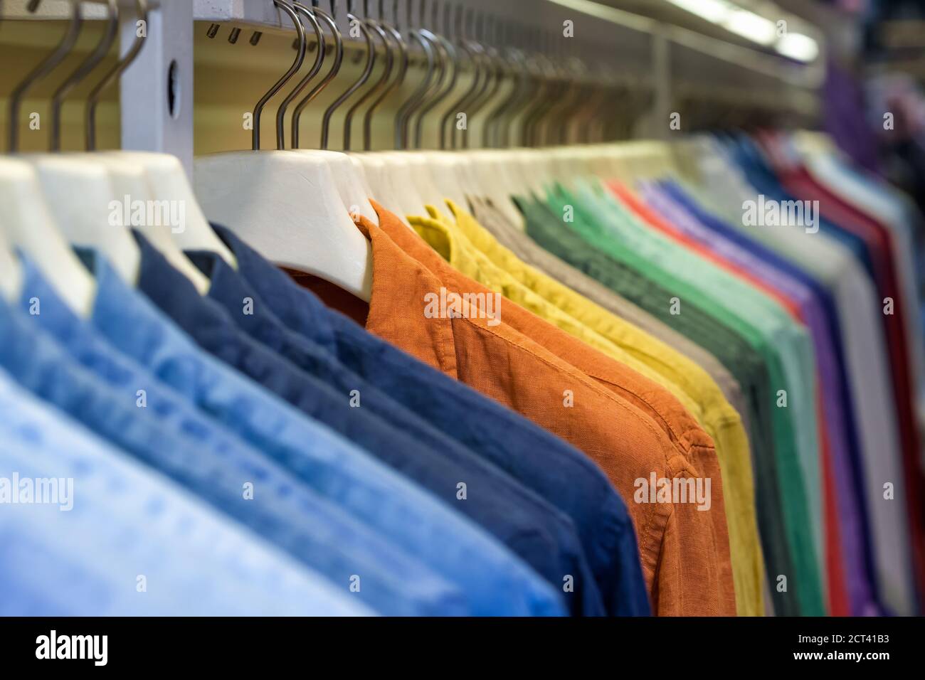 Bright colorful cotton shirts on hanger in boutique shop close up Stock Photo