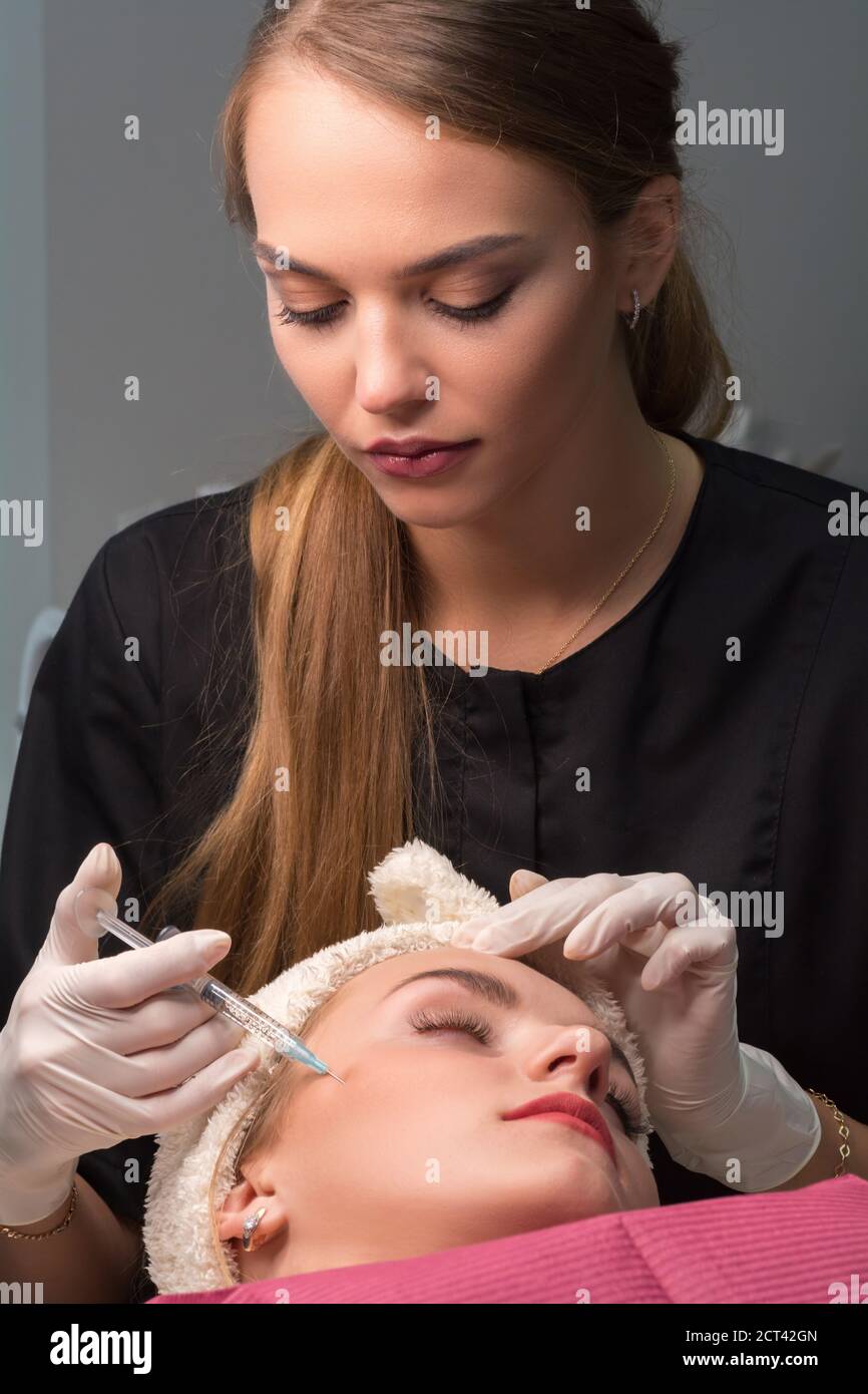 Woman getting cosmetic injection of botulinum on face. Procedure for ...