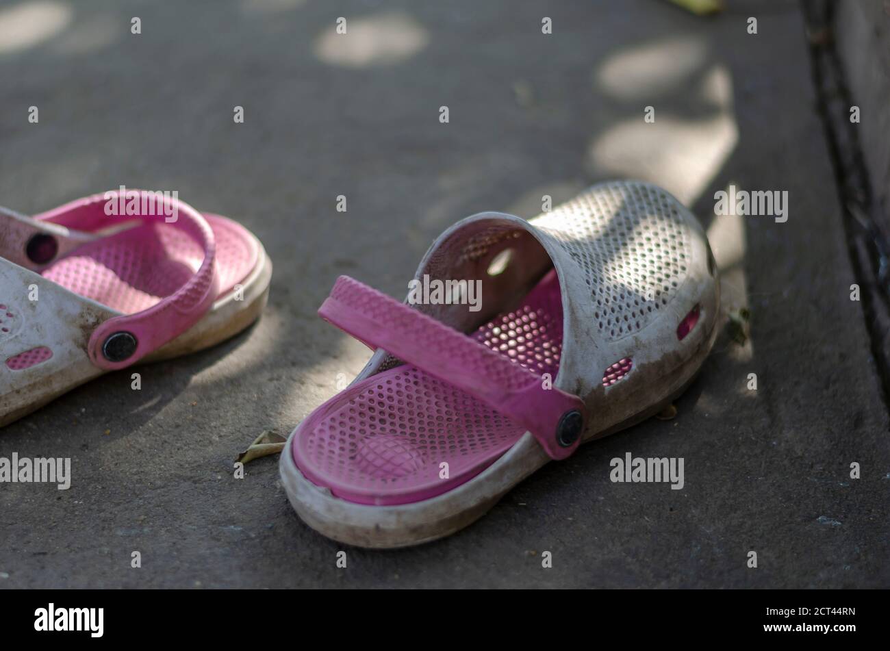 White-pink dirty summer slippers in the shade on a concrete path. Close-up  of old slippers. Selective focus Stock Photo - Alamy