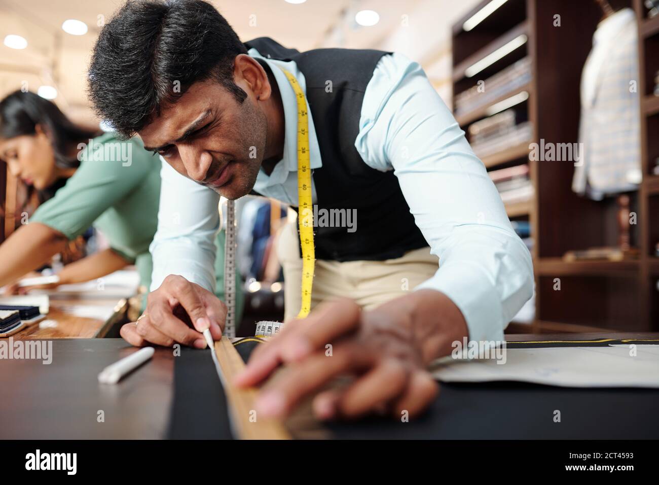 Tailor drawing line on black fabric Stock Photo Alamy