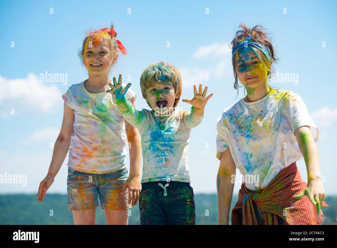 Cheerful kids showing her hands painted in bright colors. Colorful faces, color splash, coloured powder on children body. Stock Photo