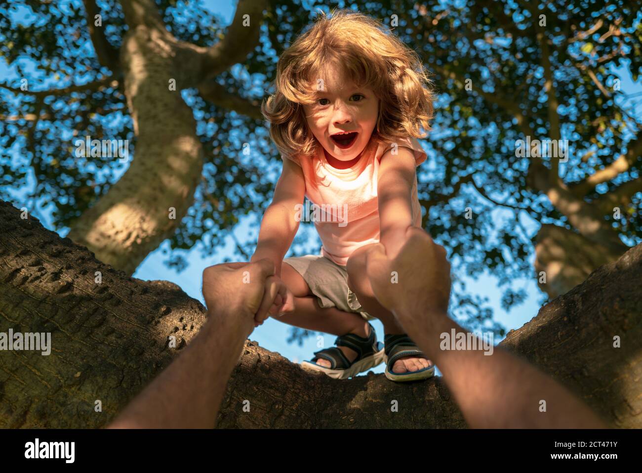 Kids climbing trees. Fathers hand. Child protection. Stock Photo