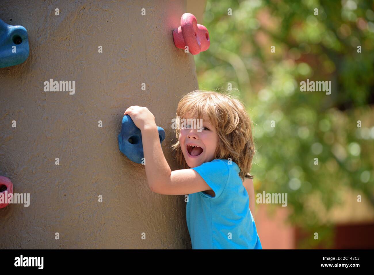 Insurance kids. Portrait of kid boy climbing on practical wall indoor, bouldering training. Health care insurance concept for family and children Stock Photo