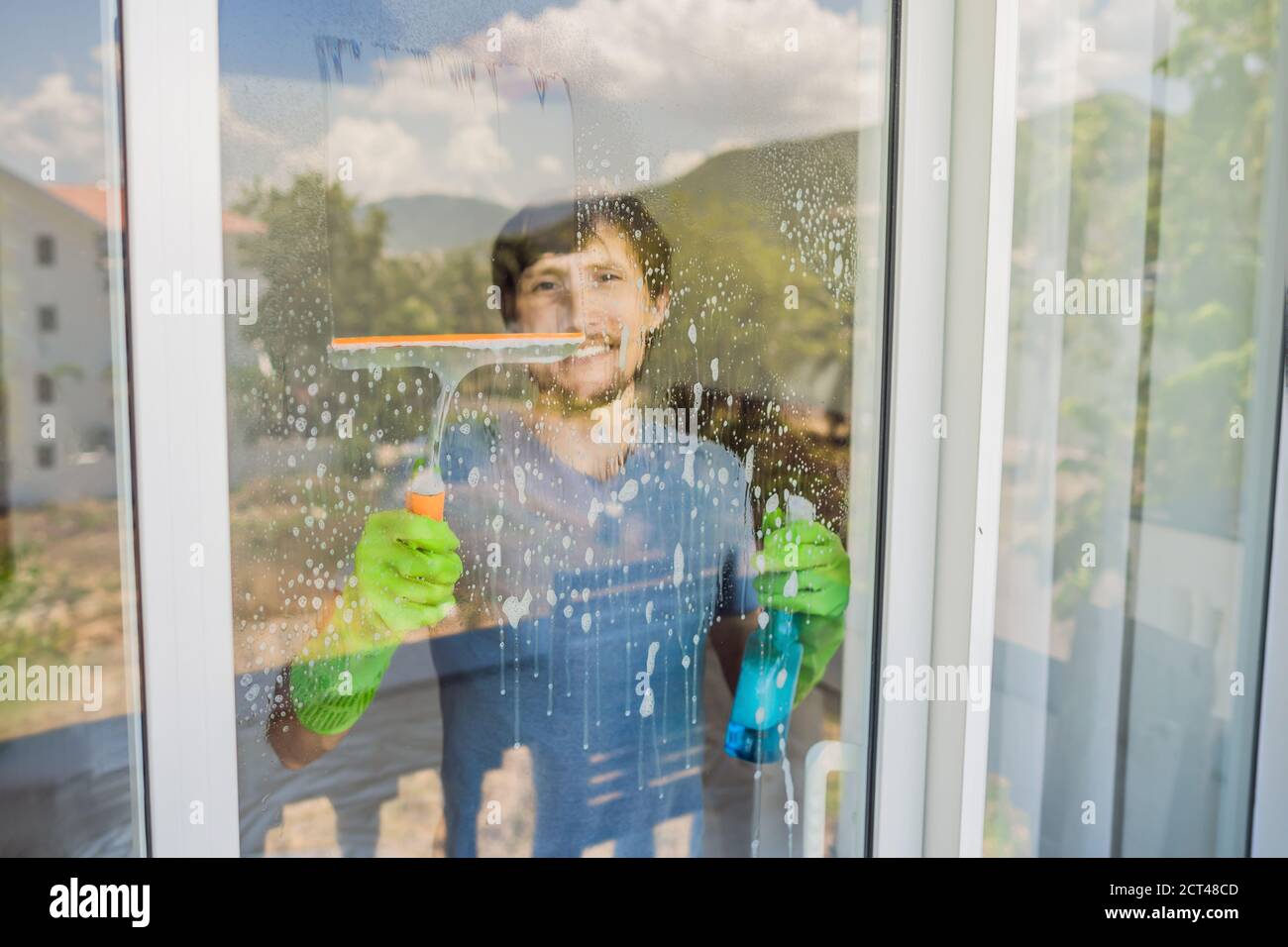 A young man cleaning the window with a window cleaner Stock Photo Alamy